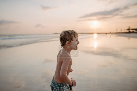 Photo for Little boy in swimsuit running out of sea, enjoying summer holiday. - Royalty Free Image