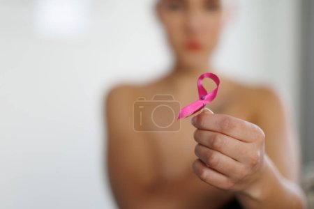 Foto de Close-up of woman holding a pink ribbon, concept of breast cancer awareness. - Imagen libre de derechos