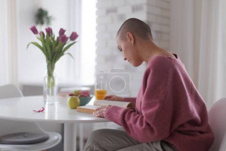 Téléchargez les photos : Young woman with cancer reading a book, cancer awareness concept. - en image libre de droit
