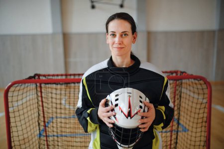Photo for A close-up of woman floorball goalkeeper in helmet concetrating on game in gym. - Royalty Free Image