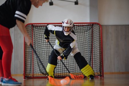 Eine Nahaufnahme der Unihockey-Torhüterin mit Helm, die sich auf ein Spiel in der Sporthalle konzentriert.