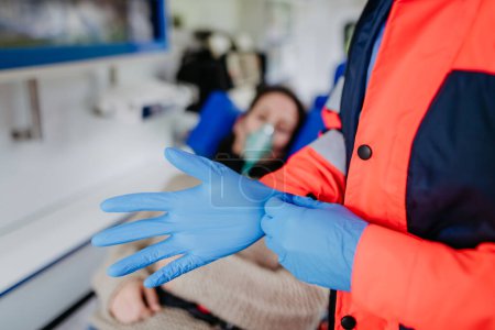 Téléchargez les photos : Close-up of a rescuer putting on surgical gloves before examination of patient. - en image libre de droit
