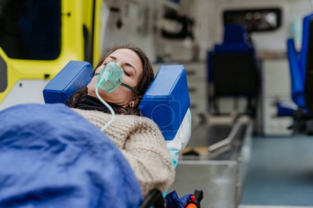 Foto de Close-up of woman patient lying in ambulance vehicle after serious accident. - Imagen libre de derechos