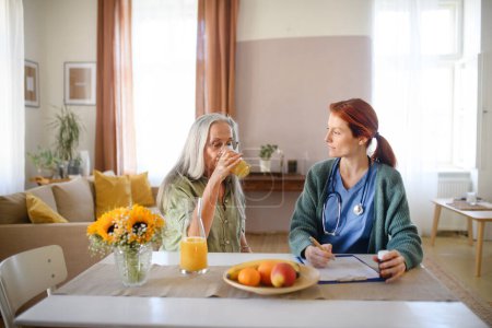 Foto de Enfermera cosulting con la mujer mayor su condición de salud en su casa. - Imagen libre de derechos