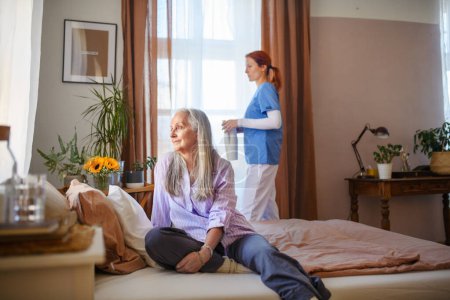 Téléchargez les photos : Caregiver helping senior woman in her home. - en image libre de droit