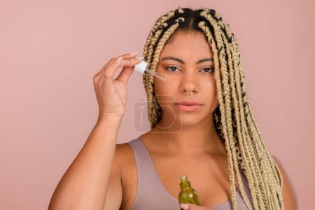 Téléchargez les photos : Portrait of young woman holding skincare serum drops in bottle.Concept of beauty and skincare. - en image libre de droit