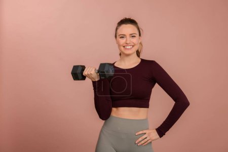 Photo for Portrait of young woman in sportive clothes with a dumbbell. - Royalty Free Image