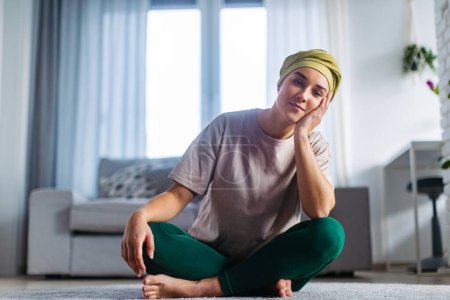 Photo for Young woman with cancer resting after taking yoga, in her apartment. - Royalty Free Image