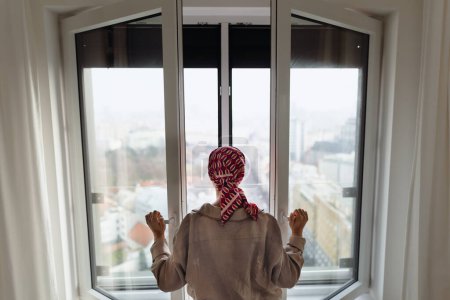 Foto de Vista trasera de una joven infeliz con cáncer de pie frente a la ventana. - Imagen libre de derechos