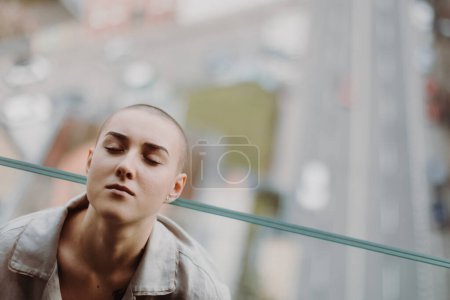 Téléchargez les photos : High angle view of young unhappy woman with cancer sitting in window. - en image libre de droit