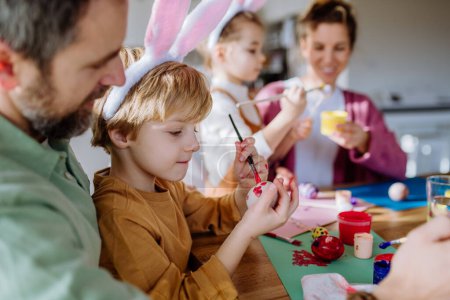 Téléchargez les photos : Happy family with little kids decorating easter eggs in their home. - en image libre de droit