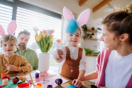 Foto de Familia feliz con niños pequeños decorando huevos de Pascua en su casa. - Imagen libre de derechos