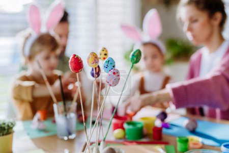 Foto de Familia feliz con niños pequeños decorando huevos de Pascua en su casa, primer plano. - Imagen libre de derechos