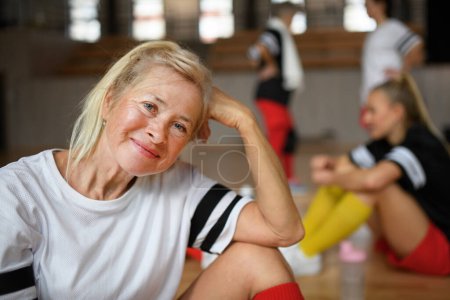 Photo for Happy senior woman stretching before basketball match in a gym. - Royalty Free Image