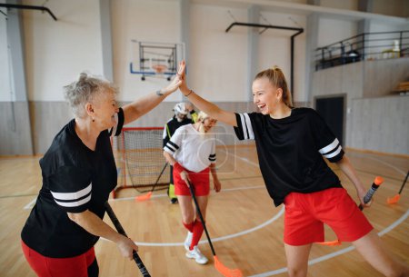 Foto de Un grupo de jóvenes y viejas mujeres alegres, jugadores del equipo de pelota de suelo, en el gimnasio cebrating victoria. - Imagen libre de derechos