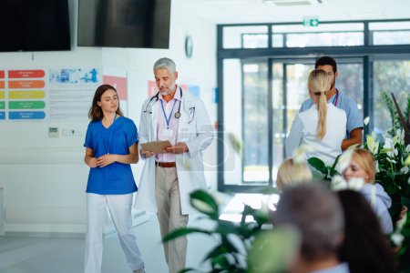 Téléchargez les photos : Équipe de médecins discutant de quelque chose dans un couloir d'hôpital. - en image libre de droit