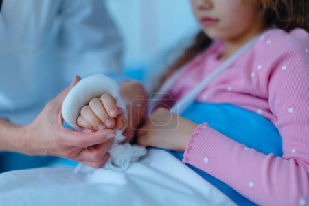 Téléchargez les photos : Médecin examinant une petite fille avec le bras cassé. - en image libre de droit