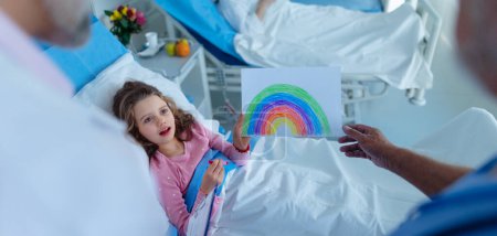 Téléchargez les photos : Petite fille dans une chambre d'hôpital a dessiné une belle image de l'arc-en-ciel, concpet de guérison et d'espoir. - en image libre de droit