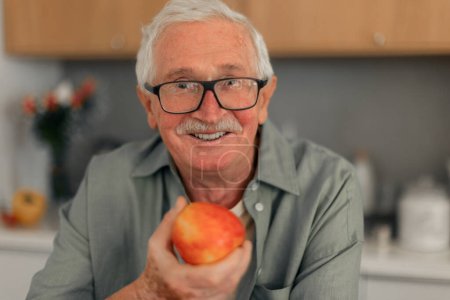 Photo for Portrait of senior man holding apples in a kitchen. - Royalty Free Image