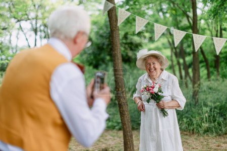 Photo for Senior couple having marriage in nature during a summer day, senior man taking photo of his wife. - Royalty Free Image
