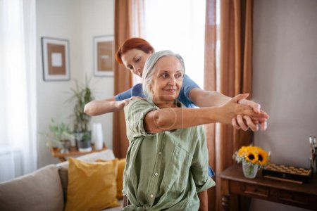 Photo for Nurse exercising with senior woman at her home, concept of a healthcare and rehabilitation. - Royalty Free Image