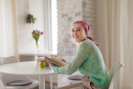 Photo for Young woman with cancer reading a book, cancer awareness concept. - Royalty Free Image