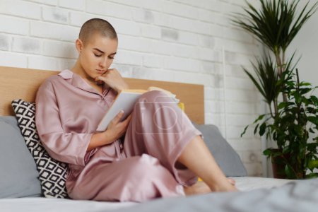 Téléchargez les photos : Young woman with cancer reading a book, cancer awareness concept. - en image libre de droit