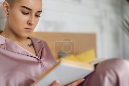 Foto de Portrait of young woman with cancer reading a book, cancer awareness concept. - Imagen libre de derechos