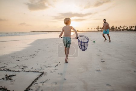 Photo for Father with his son plaing football on a beach. - Royalty Free Image