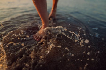 Téléchargez les photos : Femme marchant sur la plage au coucher du soleil, gros plan des pieds. - en image libre de droit