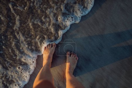 Photo for Woman walking on the beach during sunset, close-up of feet. - Royalty Free Image