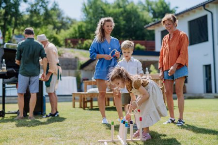 Photo for A multi generation family playing throw a ring game when grilling outside on backyard in summer at garden party. - Royalty Free Image