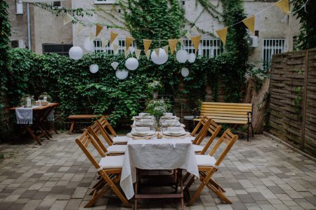 Téléchargez les photos : A festive wedding table setting with flowers at small reception in backyard in summer. - en image libre de droit