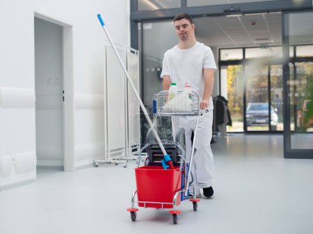 Téléchargez les photos : Young man with down syndrome working in hospital as cleaner. Concpet of integration people with disability into society. - en image libre de droit