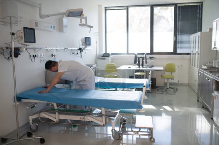 Foto de Young man with down syndome working in a hospital as helper, cleaner. Concpet of integration people with disability into society. - Imagen libre de derechos