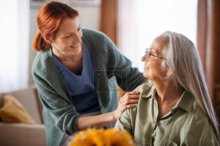 Foto de Enfermera cosulting con la mujer mayor su condición de salud en su casa. - Imagen libre de derechos