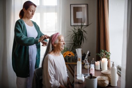 Téléchargez les photos : Aide soignante à sa cliente âgée avec une coiffure. - en image libre de droit