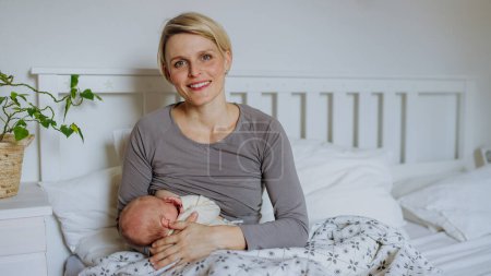 Photo for Mother brestfeeding her little baby in their bedrooom. - Royalty Free Image