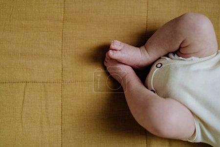 Téléchargez les photos : Close-up of babys legs lying in a bed. - en image libre de droit
