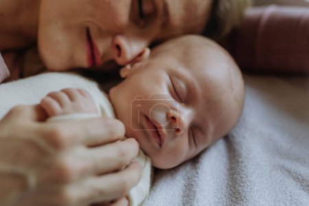 Téléchargez les photos : Close-up of mother cuddling with her newborn baby in the bad. - en image libre de droit