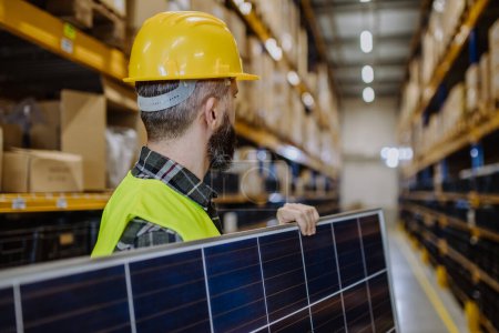 Photo for Rear view of warehouse worker carring a solar panel. - Royalty Free Image