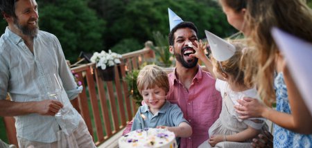 Foto de Una familia de varias generaciones celebrando cumpleaños y tienen fiesta de jardín al aire libre en el patio trasero en el patio. - Imagen libre de derechos