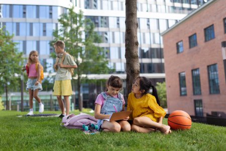 Téléchargez les photos : Happy kids playing and talking together in s city park, during summer day. - en image libre de droit