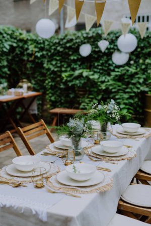 Photo for A festive wedding table setting with flowers at small reception in backyard in summer. - Royalty Free Image