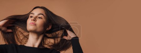 Téléchargez les photos : Portrait d'une jeune femme en studio, fond beige. - en image libre de droit