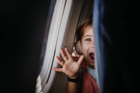 Téléchargez les photos : Little curious girl looking through seat in the airplane. - en image libre de droit
