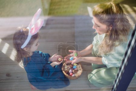 Téléchargez les photos : Petite fille tenant panier et montrant mère Pâques oeufs qu'elle a trouvé. - en image libre de droit