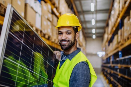 Photo for Happy warehouse worker carring a solar panel. - Royalty Free Image