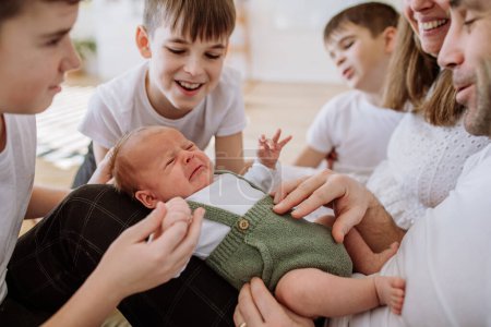 Gran familia con cuatro hijos disfrutando de su bebé recién nacido.