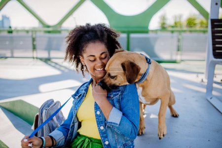 Téléchargez les photos : Multiracial girl sitting and resting with her dog outside in the bridge, training him, spending leisure time together. Concept of relationship between a dog and teenager, everyday life with pet. - en image libre de droit